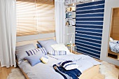 Bedroom with double bed, shelves, blinds and blue striped wallpaper