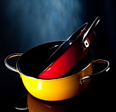 Stack of red and yellow pans on black background