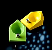 Pair of green and yellow egg cup on black background