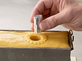 Close-up of hand inserting pastry mould in dough while preparing wild pie