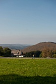 Hiker walking on road across landscape and mountains in Sauerland, Germany