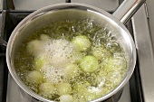 Onions being blanched with salt water in pot, step 1