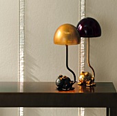 Two frog table lamps on table in front of non-woven wallpaper