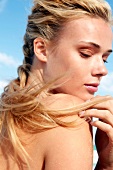 Blonde woman with long braided hair looking over her shoulder