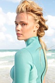 Blonde woman with long, braided hair in a green diving suit