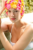 A woman wearing makeup with a colorful bathing cap looking into the camera