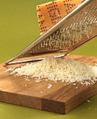 Parmesan being grated using grater on wooden block
