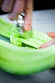 Close-up of hand removing cucumber seeds with spoon, blurred motion