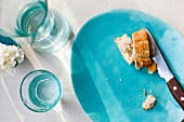 Slices of bread and knife on blue plate, overhead view