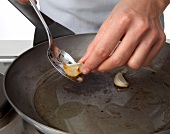 Garlic cloves being fried in pan