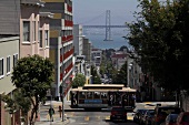 People travelling in tram and Bay bridge in background at San Francisco, California, US
