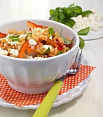 Bowl of lentil salad with feta on plate with fork and checked orange table mat