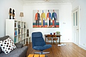 Gray couch, blue swivel chair and white shelves in living room with painting on wall