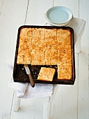 Sliced coconut lime sheet cake in baking tray
