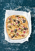 Sheet cake of focaccia with figs and rosemary on baking paper
