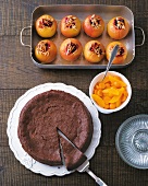 Baked apples in baking tray and chocolate cake on plate, overhead view