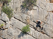 Man climbing rock mountain at Caletta Fuili, Cala Gonone, Sardinia, Italy