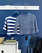 Knitted sweater in blue and white hanging against blue background