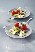 Warm tomato salad with layer of cheese and capers on plate