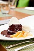 Chocolate souffle garnished with pear sorbet, chocolate sauce and whipped cream on plate