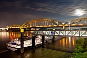 View of ship under Hohenzollern Bridge in Rhine at night, Cologne, Germany