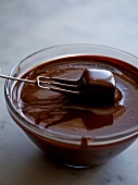 Chocolate dipped with praline fork in bowl of chocolate sauce