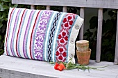 Knitted colourful cushion cover with flowers on table