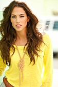Portrait of beautiful woman with long dark hair wearing yellow top and chain