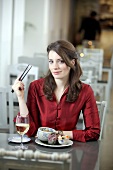 Portrait of woman eating with chopsticks and holding glass of white wine in restaurant