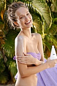 Woman with blonde hair applies lotion on her shoulder