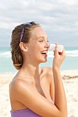 Woman creams her nose with sun blocker