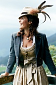 Woman in dirndl dress and hat with springs for Oktoberfest looking sideways, smiling