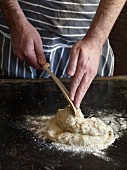 Close-up of hand folding dough with dough scraper