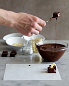 Chocolate blocks being dipped in melted chocolate with praline fork, step 1