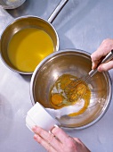 Sugar powder being added to eggs in bowl