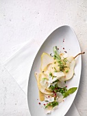Pear-Pecorino carpaccio with lemon and pea vinaigrette in serving dish, overhead view