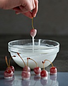 Cherries being dipped in sugar syrup