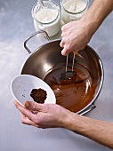 Adding triturated pepper to melted chocolate in bowl