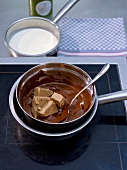 Melting chocolate and nougat in bowl on saucepan with boiling water