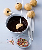 Cake pop being dipped in bowl of liquid chocolate