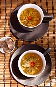 Two cups of tea with flower heads