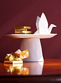 Origami crane and chocolate with gold wrapper on porcelain plate