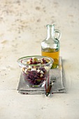 Vegetable salad in glass bowl with oil in carafe