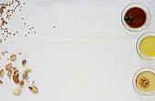 Nuts and bowls of oil on white background