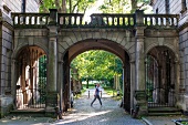 Woman passing at gatehouse in old garden, Hannover, Germany