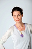 Portrait of woman wearing white top and chain with purple pendant, smiling