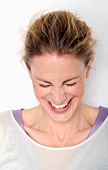 Close-up of happy woman wearing white top laughing with eyes closed