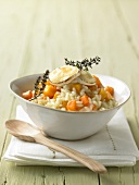 Pumpkin and carrot risotto with melted goat cheese in bowl