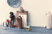 Glass of drink, jars, chopping boards and figurine on table