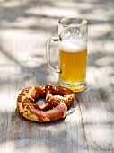 Pretzel and glass of beer on wooden surface, Bavaria, Germany